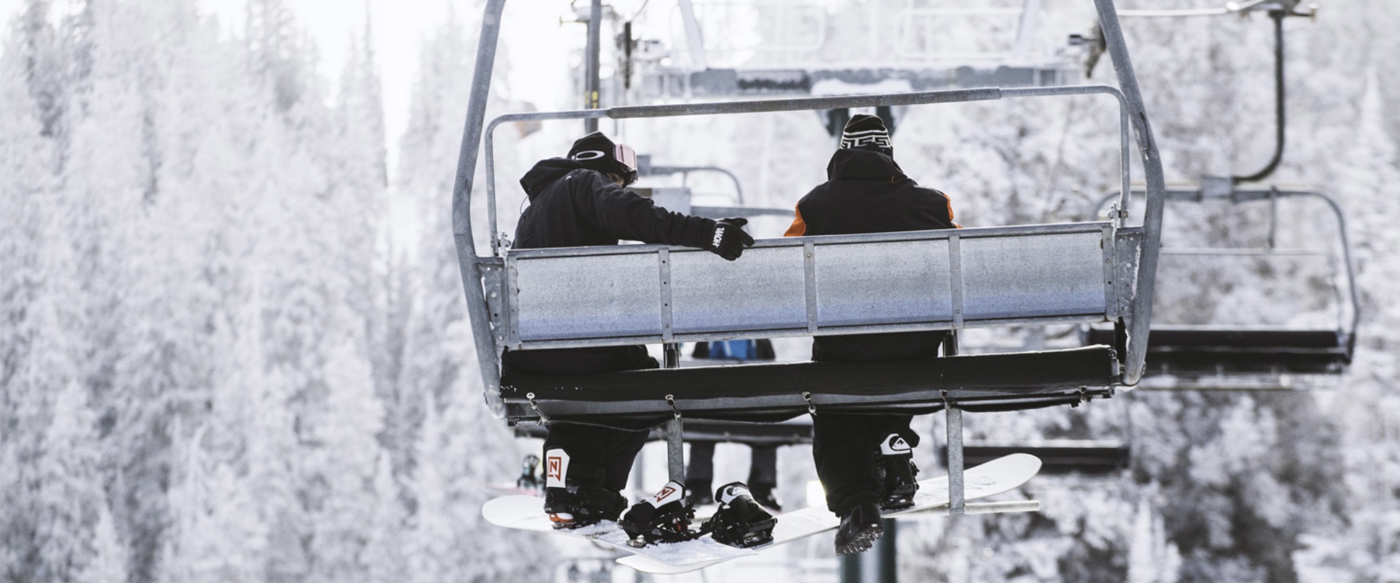 Snowboarders riding a snowy lift at Brighton Resort